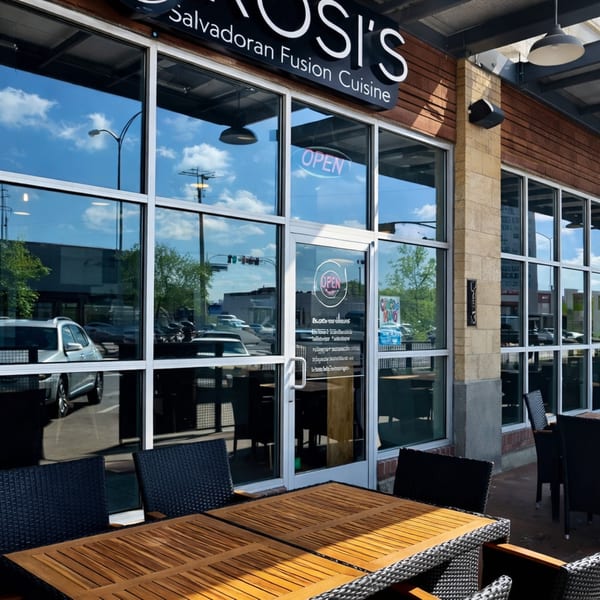 Exterior of ROSI'S Salvoradan Fusion Cuisine restaurant with outdoor seating and large windows.