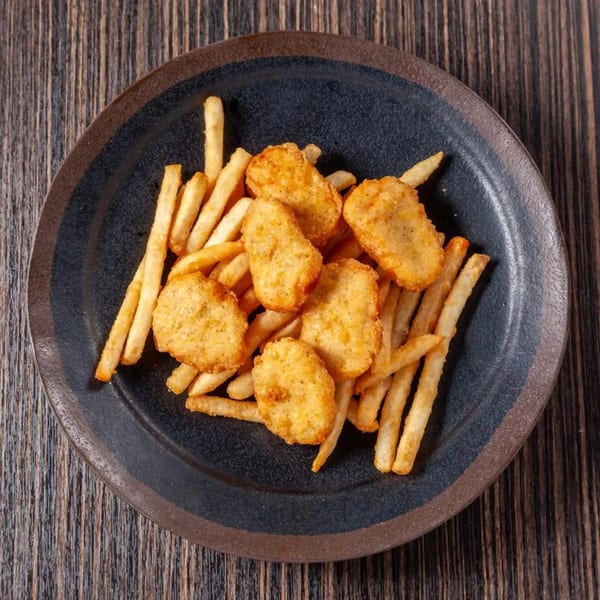 Golden chicken nuggets and crispy french fries served on a dark plate.