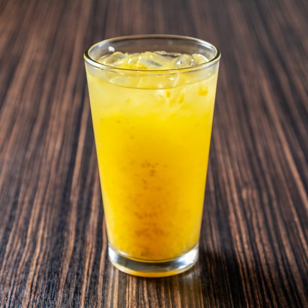 Refreshing glass of iced orange juice on a dark wooden table.