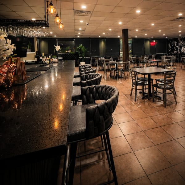 Empty restaurant interior with a long bar, bar stools, and dining tables with chairs.